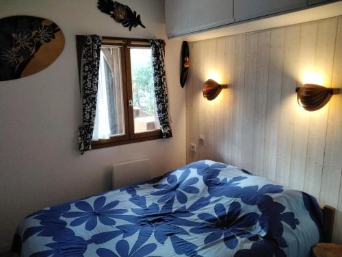 a bedroom with a blue and white comforter on a bed at CHALET A NATURISTE Le TIKI in Le Porge