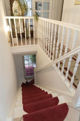a stairway with a red rug and a white staircase at Petit Wannsee GmbH in Berlin