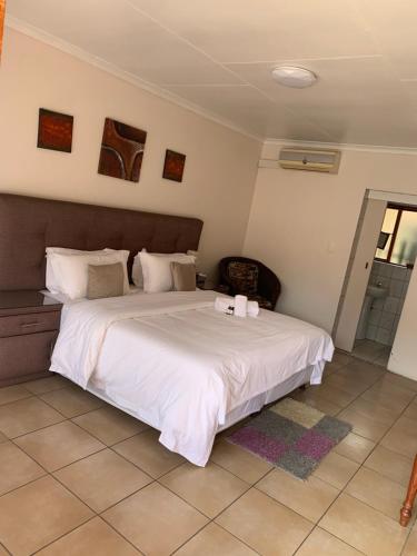 a bedroom with a large bed with white sheets at Lens BnB Guesthouse in Benoni