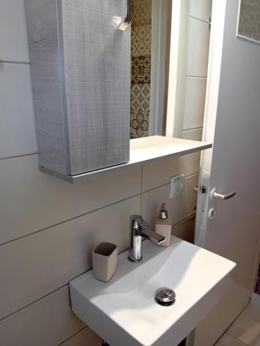 a bathroom with a white sink and a mirror at Lourantos Studios & Apartments in Vathi