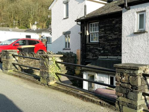 a house with a fence and a red car on a street at Stockdale Cottage in Ambleside