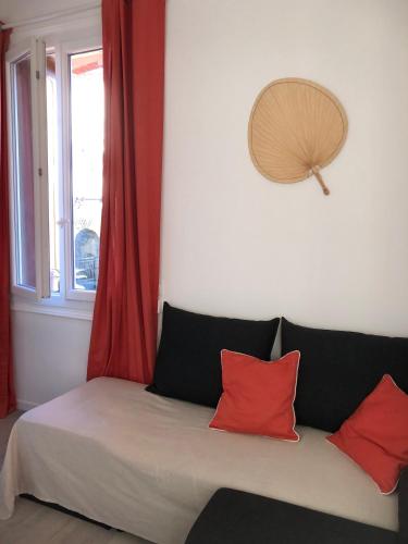 a bed with two red pillows and a window at Un petit nid au calme, à 4 minutes de la plage ! in Banyuls-sur-Mer