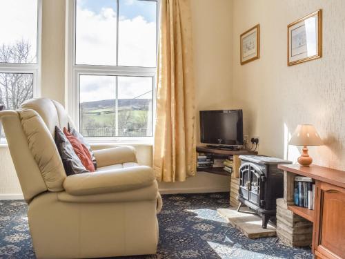 a living room with a chair and a television at Whitby Apartment in Commondale