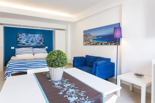 a living room with a bed and a blue chair at Mondello Suites Feels Like Home in Mondello