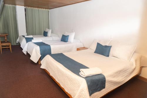 a hotel room with three beds with blue pillows at HOTEL SUAREL CENTER in Duitama