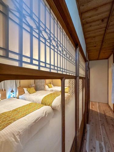 two bunk beds in a room with wooden ceilings at PolePole in Takamatsu