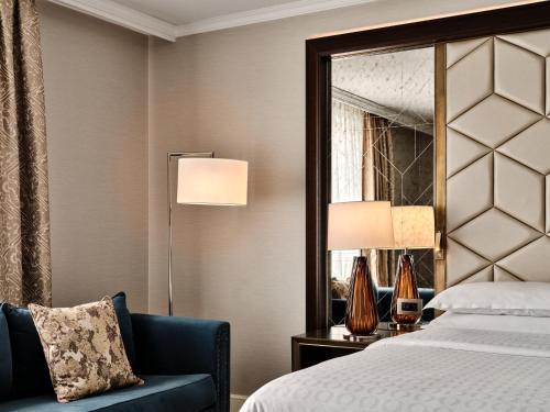 a bedroom with a bed and a chair and a mirror at Sheraton Grand Warsaw in Warsaw