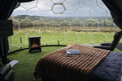 a bedroom with a bed and a fireplace in a tent at Glamping Domes in Articlave