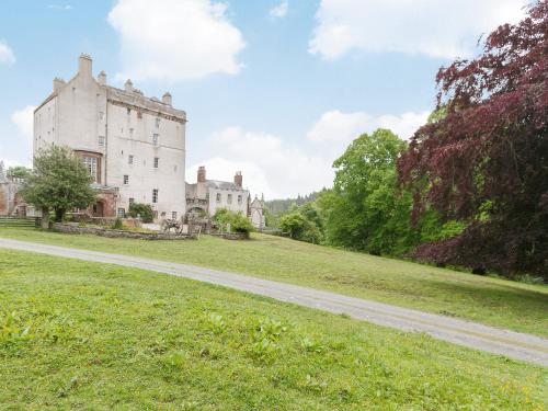 an old castle on a grassy hill with a dirt road at Symbister Suite in Turriff