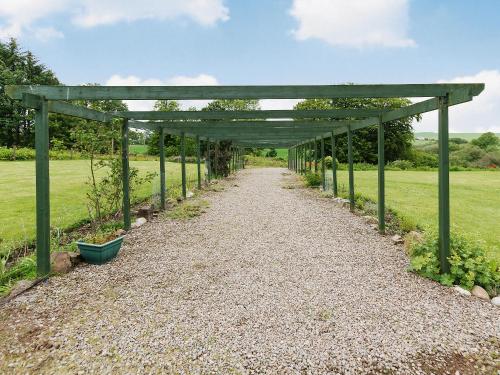 a wooden pergola over a gravel path at Symbister Suite in Turriff