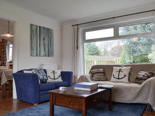 a living room with a couch and a table and a window at Sea Breezes in Totland