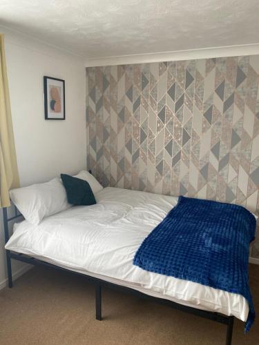 a bed with a blue blanket on top of it at Charming Contractors & Family Friendly 3-BR House in Harlow, Essex in Great Parndon