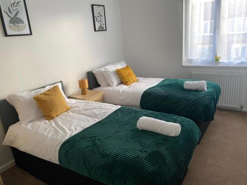 a bedroom with two beds with green and white sheets at Charming Contractors & Family Friendly 3-BR House in Harlow, Essex in Great Parndon