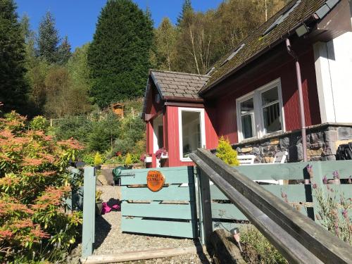 a small house with a fence in front of it at Dream Cottage in Strathyre