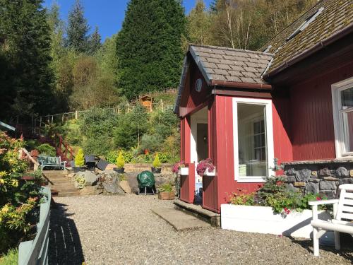 a red house with a garden in the background at Dream Cottage in Strathyre