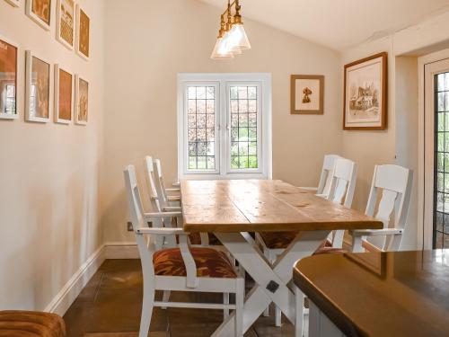 a dining room with a wooden table and white chairs at Flanders Cottage in Lymington