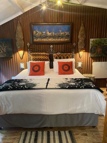 a bedroom with a large white bed with orange pillows at Bohemian Garden Cottages in Kaapsehoop