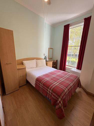 a bedroom with a bed with a plaid blanket and a window at European Hotel in London