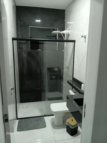 a bathroom with a glass shower and a toilet at Casa nova, completa, 3 quartos 1 com ar condicionado in Hortolândia