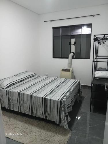 a white bedroom with a bed and a window at Casa nova, completa, 3 quartos 1 com ar condicionado in Hortolândia