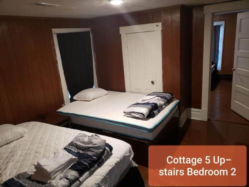 two beds in a small room with a sign that says cottage upstatus baths at Cottage 5 Duplex in Eckman ATV Fun and Rentals! in Northfork