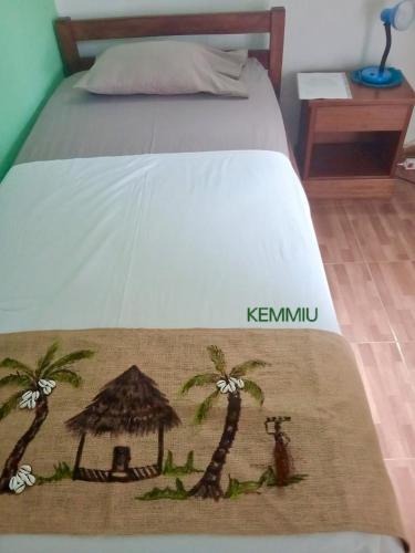 a bed with a white bedspread with palm trees on it at Kemmiu single room in São Tomé