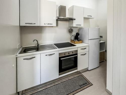 Eine Küche mit weißen Schränken, Spüle und Kühlschrank in der Unterkunft Corte Dolia in Dolianova