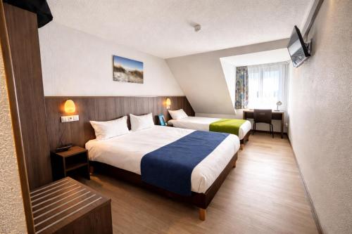 a hotel room with two beds and a table at Brit Hotel Calais in Calais