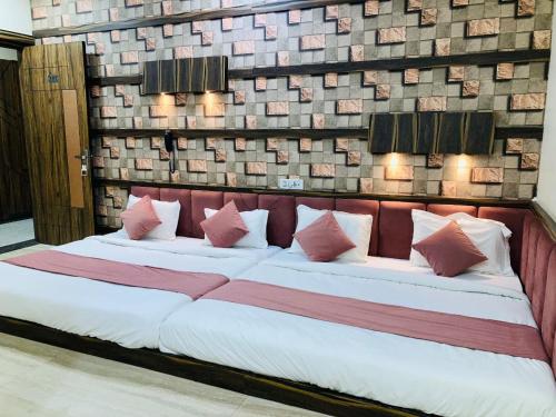 a large bed with pink and white pillows on it at Hotel SR Siddhivinayak Mathura in Mathura