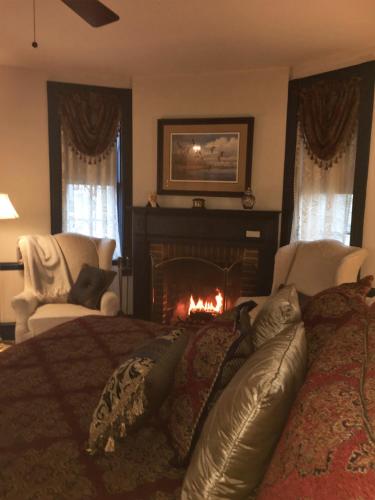 a bedroom with a bed with a fire in a fireplace at Parsonage Inn Bed and Breakfast in Saint Michaels