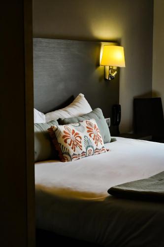 a bedroom with a large bed with pillows on it at Logis Hôtel Le Mas De Jossyl in La Roque-dʼAnthéron