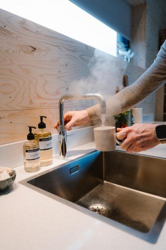 a person is washing a cup in a kitchen sink at Polderlodge de Ontmoeting in Goudriaan