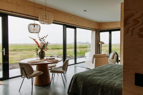 a bedroom with a bed and a table and chairs at Polderlodge de Ontmoeting in Goudriaan