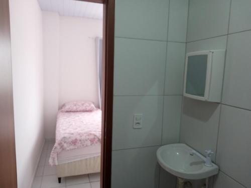 a small bathroom with a sink and a bed at Apartamento in Parnamirim