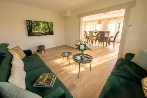 a living room with a green couch and a table at Villa 10-14 guests - 180m2 - private forest - CDG 7min - Disney 20min in Claye-Souilly