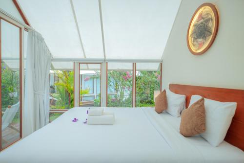 a bedroom with a white bed with a clock on the wall at Svargan Lakeside Glamping in Tabanan