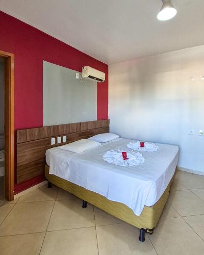 a bedroom with a bed with two red cups on it at Carlton Plaza Torre in Araxá