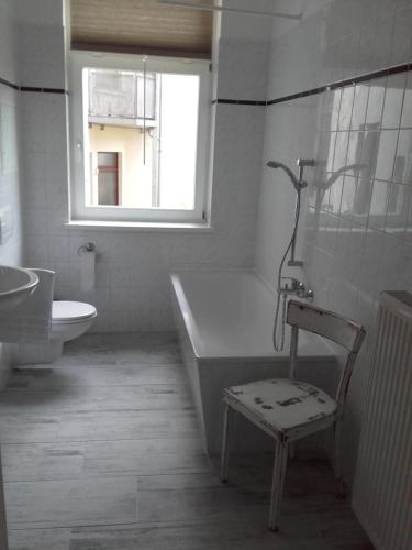 bagno con vasca, sedia e lavandino di Apartment am Kanal a Lipsia