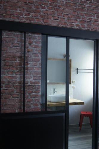 a bathroom with a sink and a brick wall at L’Antre d’Eux in Carcassonne
