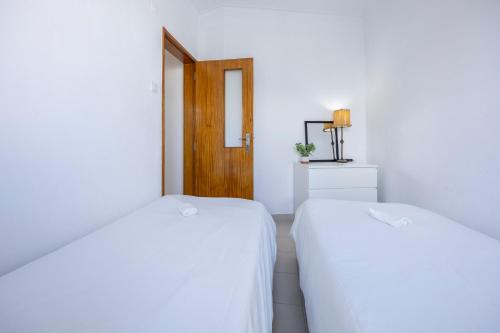 two white beds in a room with a door at Incredible view - T2 Ribeirinha in Portimão