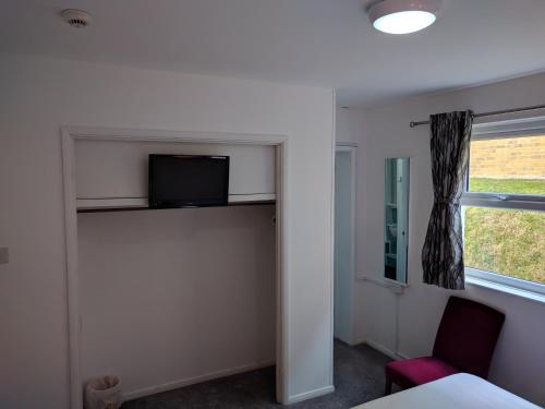 a room with a bed and a tv and a window at Mayfair Hotel -Isle of Wight in Shanklin