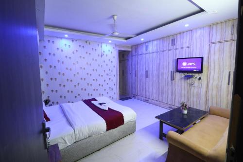 a bedroom with a bed and a couch and a tv at Hotel Yuvraj 5 Mints walking from Rajendra Nagar Metro Station in Ghaziabad
