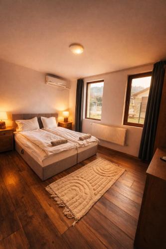a bedroom with a large bed and two windows at ng royal in Rakitovo