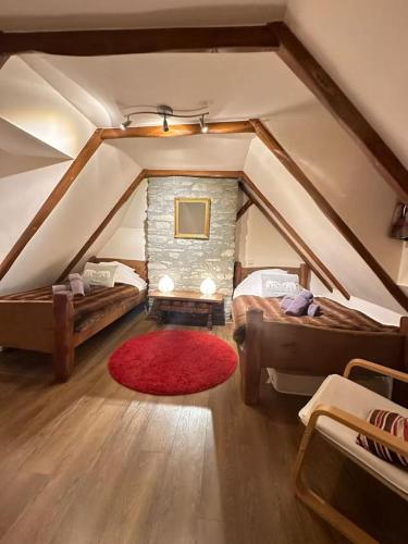 a attic room with two beds and a red rug at L'Ancienne Poste Exclusive Alpine Chalet in Avajan
