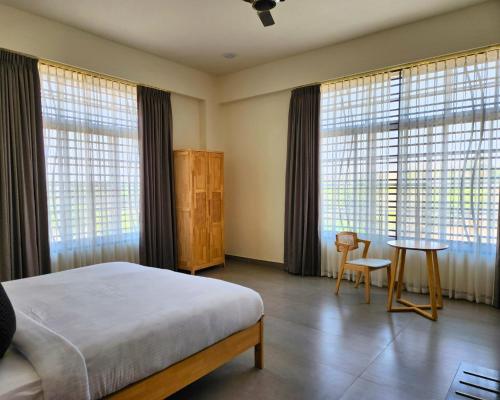 a bedroom with a bed and a table and windows at Atmosfera Bengaluru, India in Bangalore