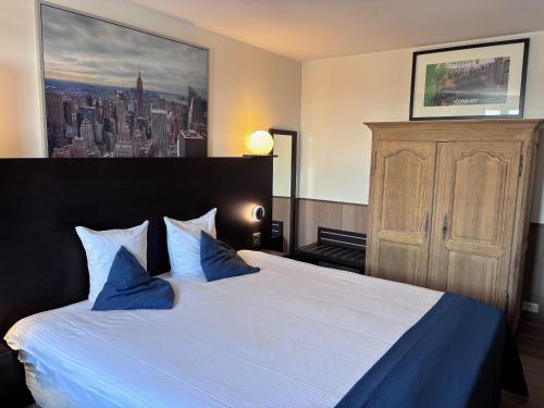 a bedroom with a large bed with blue pillows at Hotel Orchidee in Aalter