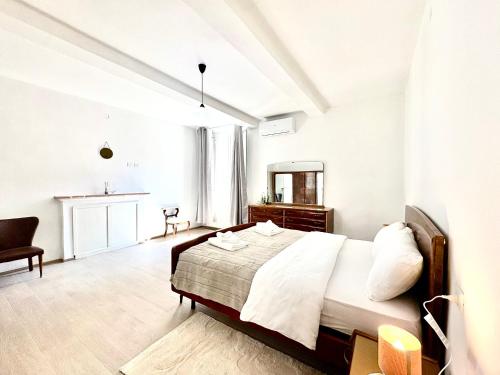 a white bedroom with a bed and a mirror at Casa in Centro con Giardino in Imola