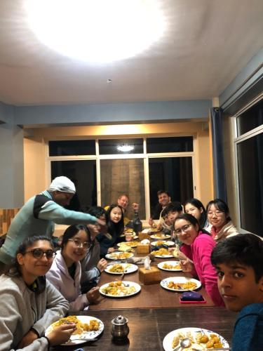a group of people sitting around a table eating food at Hotel New Manakamana in Pāti Bhanjyāng