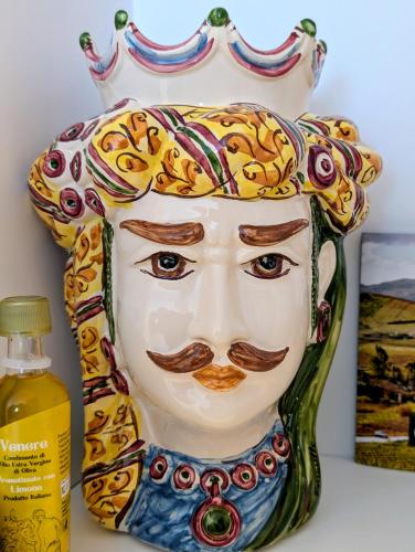 Eine Vase mit einem Gesicht darauf neben einer Flasche in der Unterkunft CI VULIA B&B - Sicilia, con colazione, piscina, barbecue, parcheggio, free wifi, sea pool and bbq in Alcamo Marina