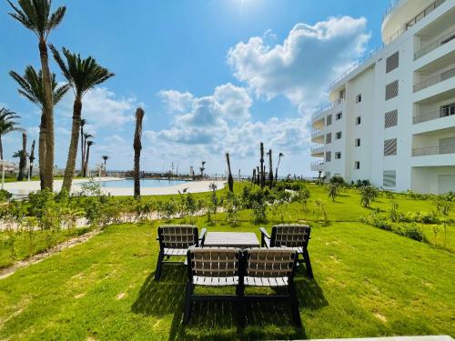 a table and chairs in a park next to a building at Apparemment s1 vu sur mer et piscine in Zarzis